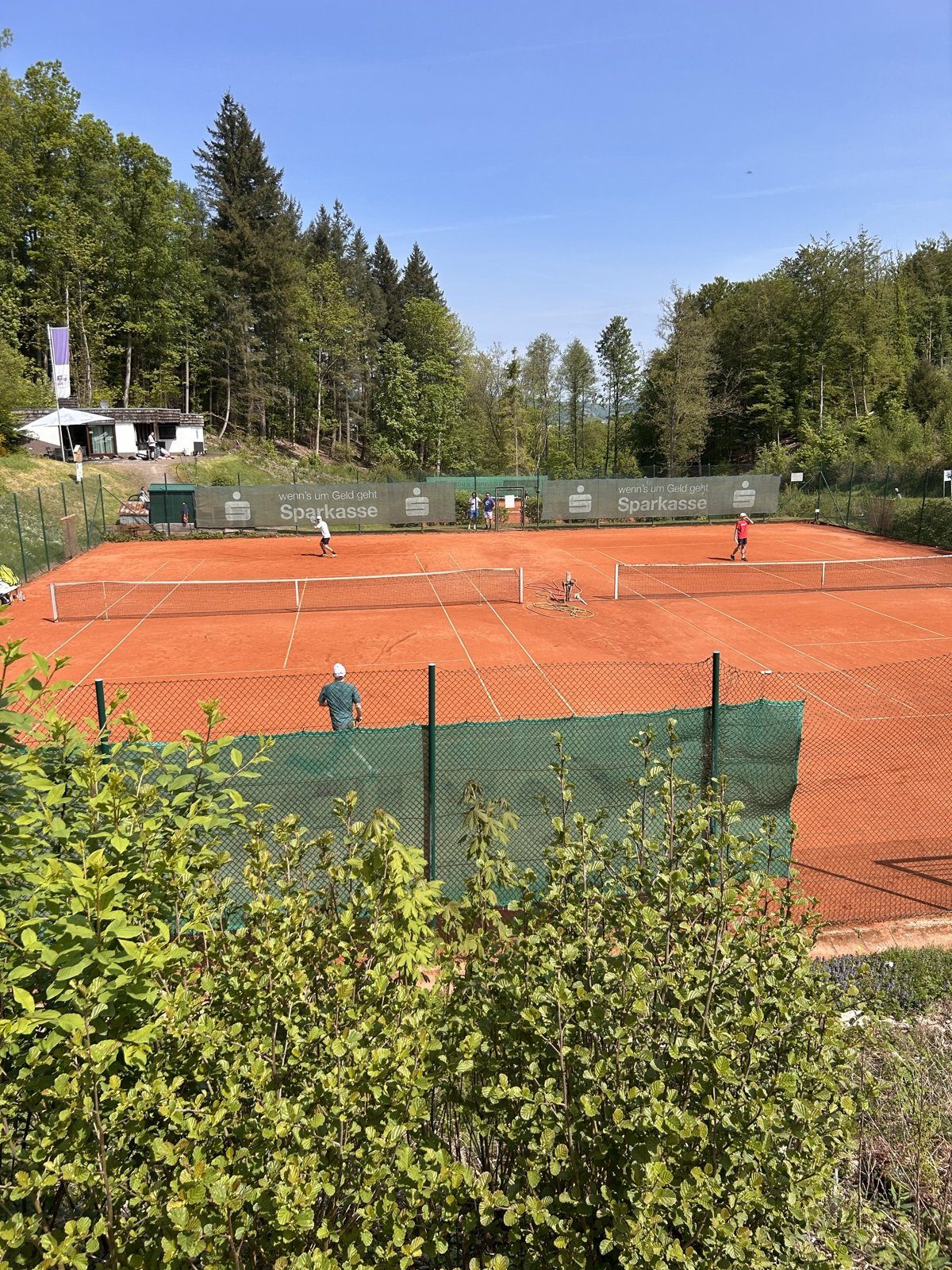 Match auf der Sandplatz-Anlage bei Sonne und blauem Himmel