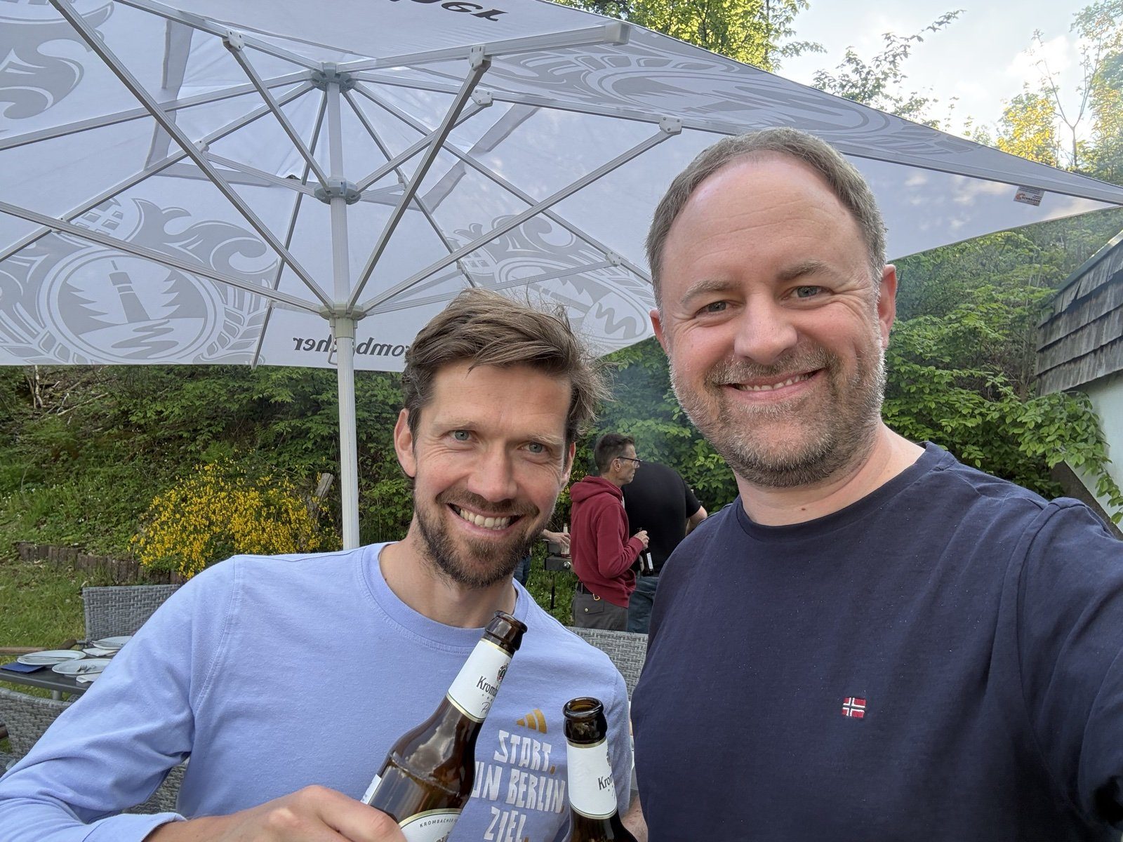 Vereinsleben: zwei Spieler stoßen mit Bier unter dem Sonnenschirm an